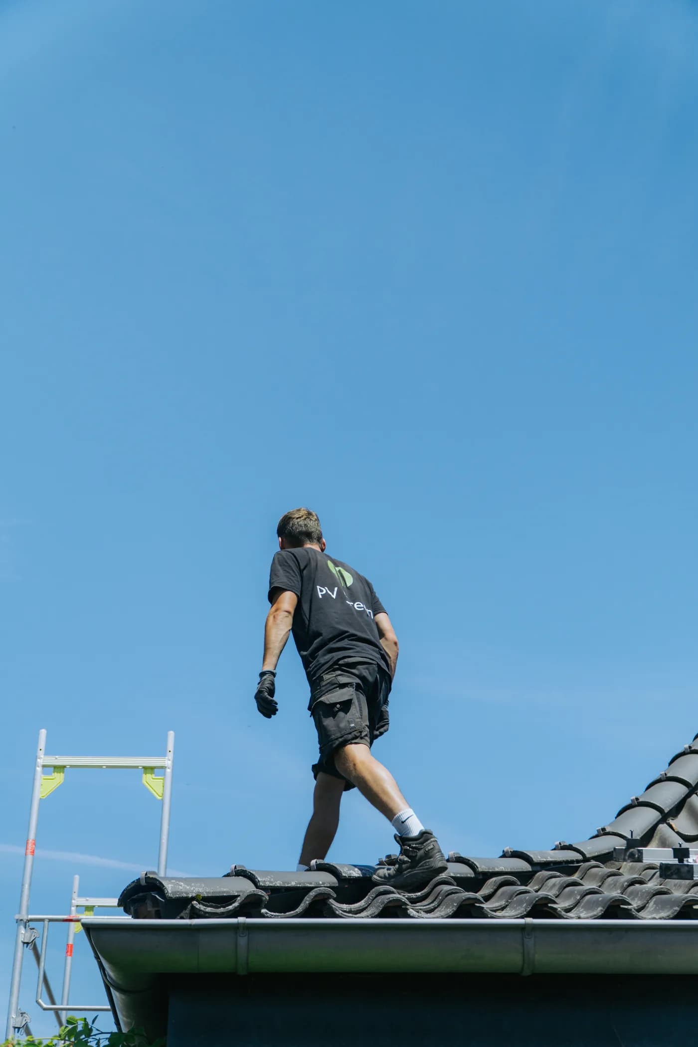 Monteur auf dem Dachfirst montiert Photovoltaik