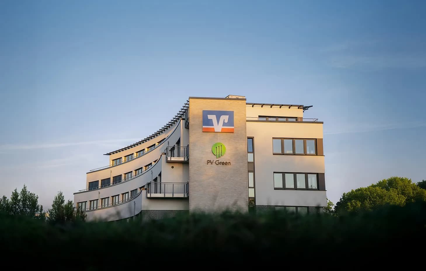 Die Zentrale von PV Green mit Logo an der Fassade im Abendlicht