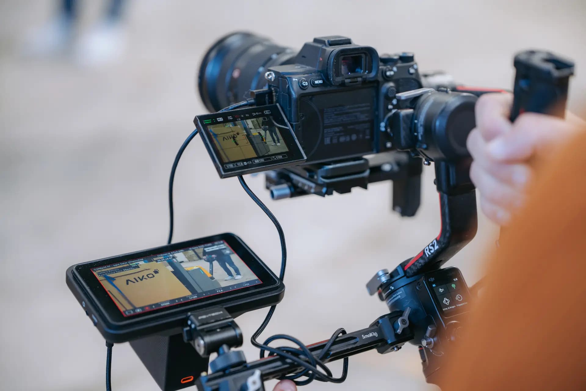 Kameramann des PV-Green-Kamerateams mit Gimbal, auf dem Monitor eine Baustelle
