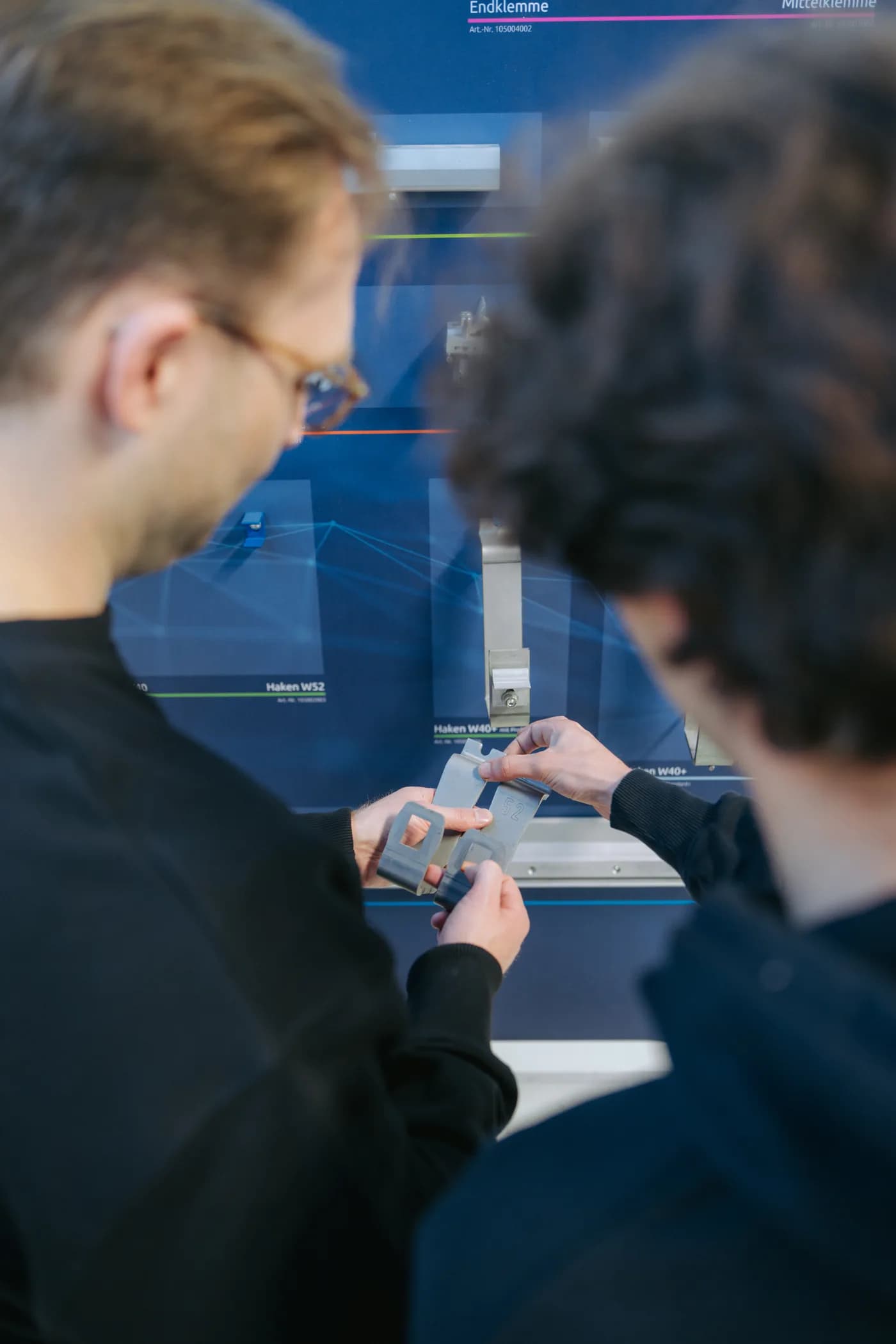 Zwei Personen vergleichen Modulklemmen vor einer Produktübersicht